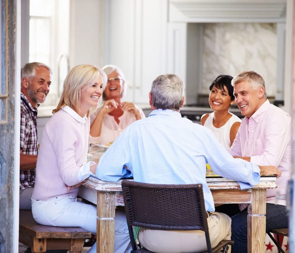 Group of people sitting arounds a table happy and laughing 