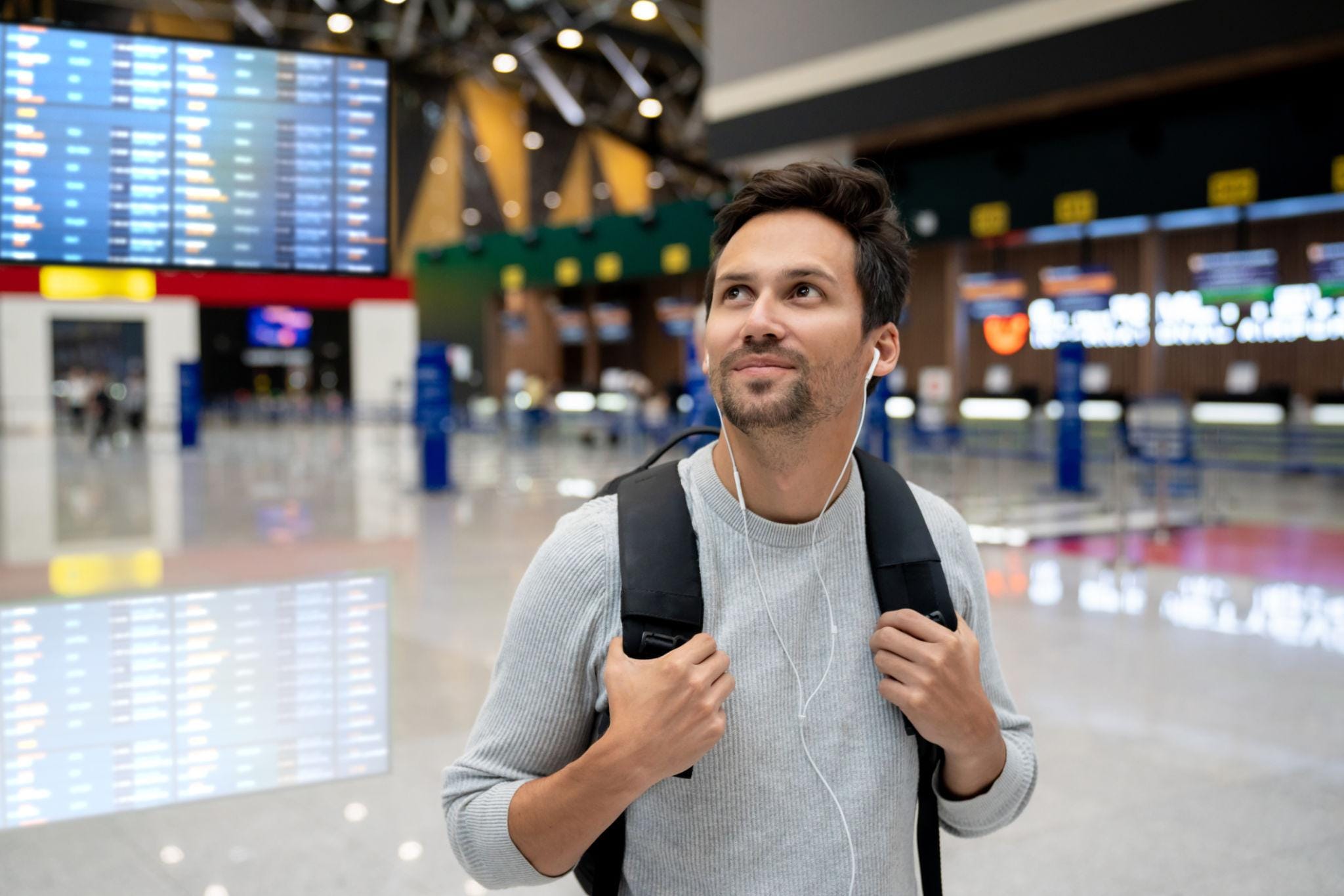 man walking through airport wearing ear buds